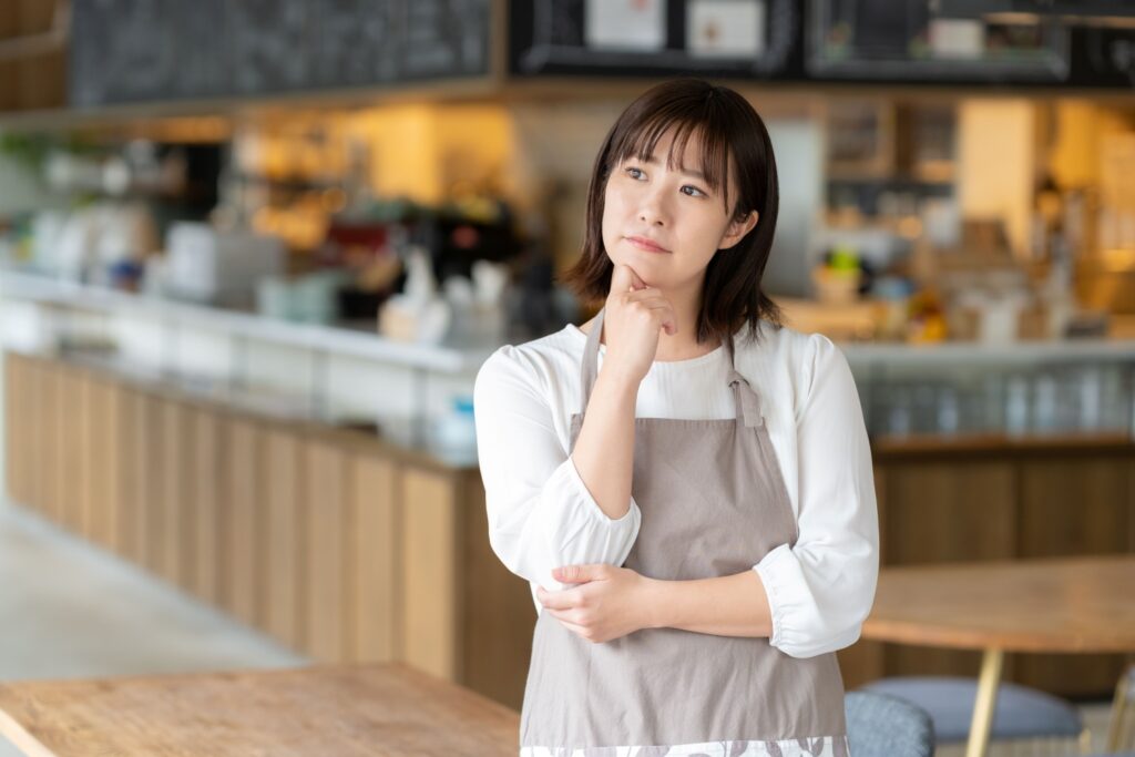 カフェで働く若い女性の店員が悩んでいる姿